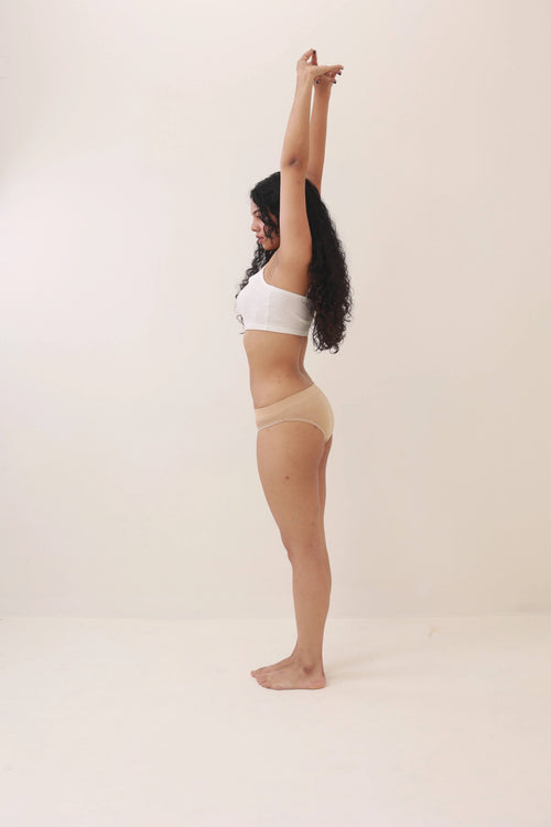a woman in beige underwear stretching her arms