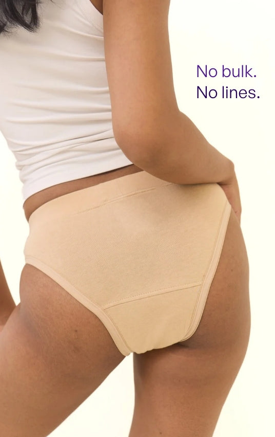 A model wearing beige high-waisted seamless underwear, shown from the waist down against a white background with purple text that reads 'No bulk. No lines.